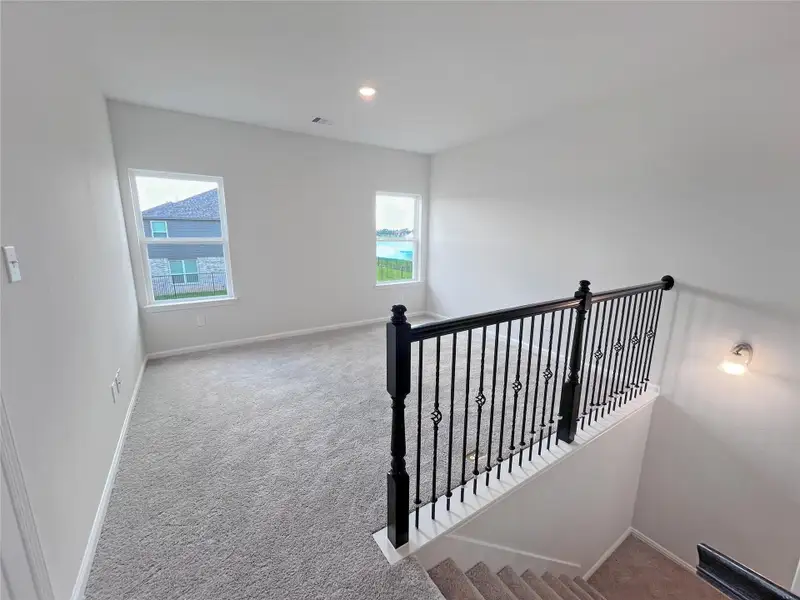 The Georgetown II- Upstairs Bonus Room/Game Room with Wrought Iron Railing. Home under construction. Sample floor plan photo used for illustrative purposes only. Upgrades, selections options, windows and colors may vary.