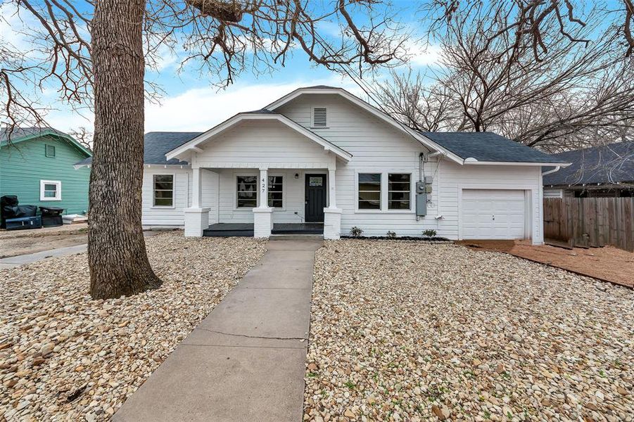 View of front of home featuring covered porch, roof with shingles, an attached garage, and fence