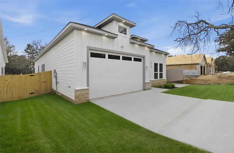 View of front of home with driveway, a garage, stone siding, and board and batten siding