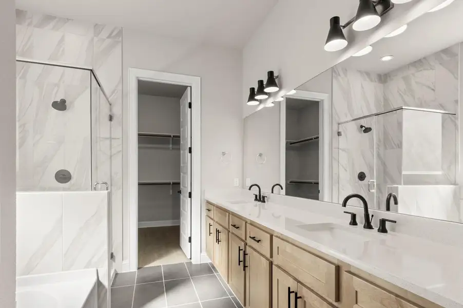 Full bath featuring a marble finish shower, double vanity, a walk in closet, dark tile patterned flooring, and a tub to relax in Full bath featuring a marble finish shower, double vanity, a walk in closet, dark tile patterned flooring, and a tub to relax in