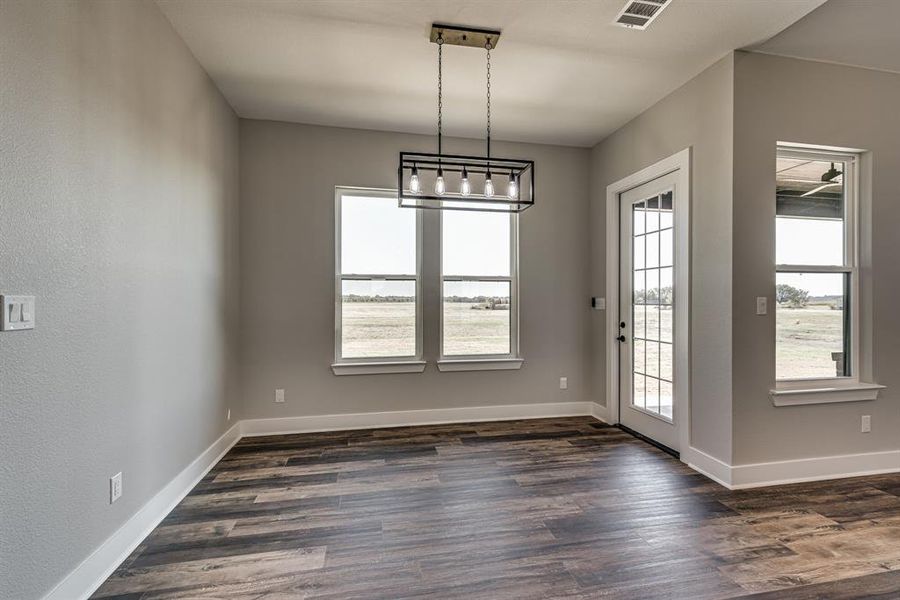 Unfurnished dining area featuring a notable chandelier and dark hardwood / wood-style floors