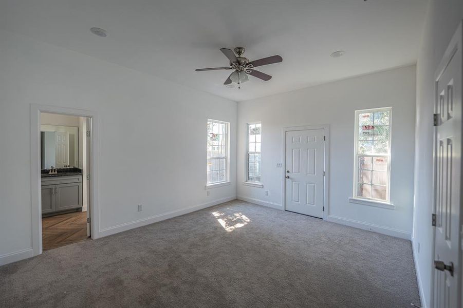 Unfurnished bedroom featuring carpet floors, ceiling fan, and ensuite bathroom