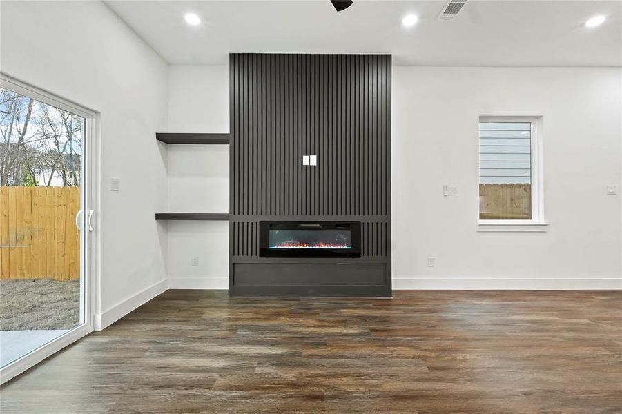 Unfurnished living room with dark wood-style floors, recessed lighting, a glass covered fireplace, and a ceiling fan