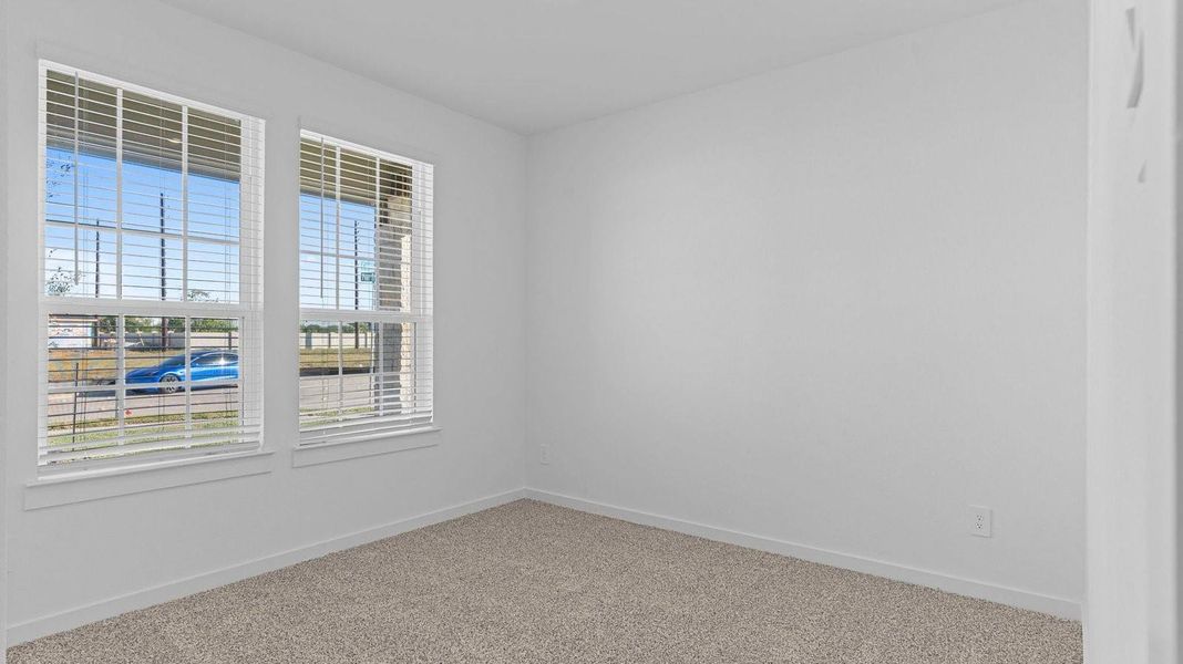A bedroom shown as an at home office with a bright window allowing natural light to enter.