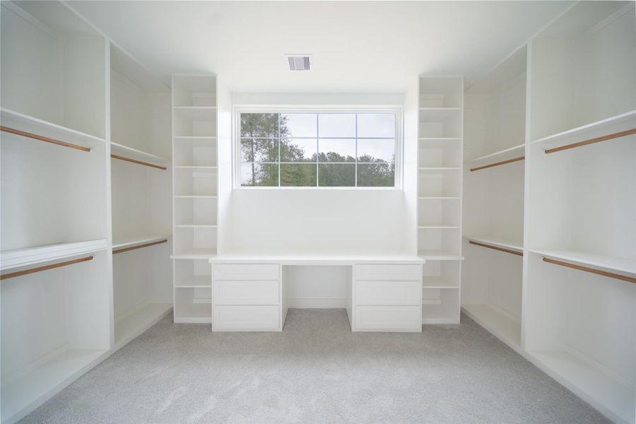 Primary bedroom closet with PLENTY of space & natural light. Also, features a vanity area for convenience
