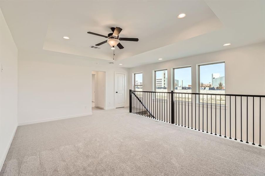 Carpeted spare room with a raised ceiling and ceiling fan