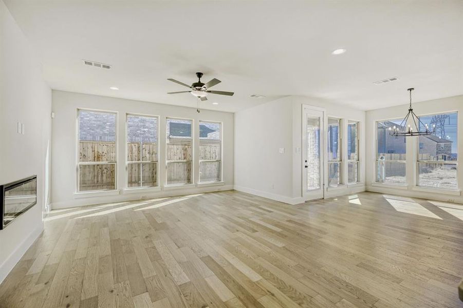 Unfurnished living room featuring suspended lighting, light wood finished floors, and a ceiling fan