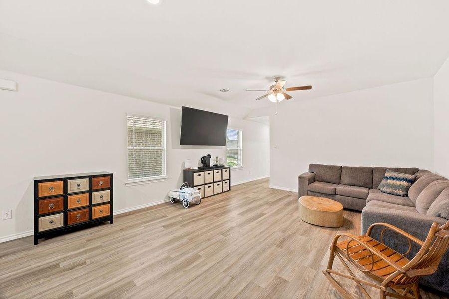 Spacious living area featuring light wood-finish flooring, recessed lighting, and a ceiling fan Spacious living area featuring light wood-finish flooring, recessed lighting, and a ceiling fan