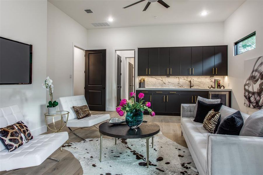 Living room with wine cooler, ceiling fan, sink, and light wood-type flooring