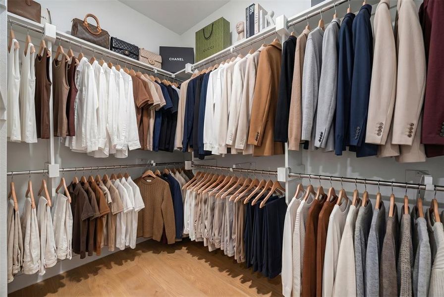 Custom-built closet system featuring multiple hanging rods, integrated shelving, and wood-finish flooring