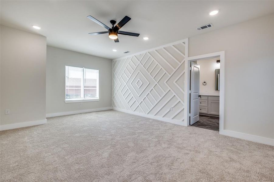 Unfurnished bedroom with a ceiling fan, light colored carpet, connected bathroom, an accent wall, and recessed lighting
