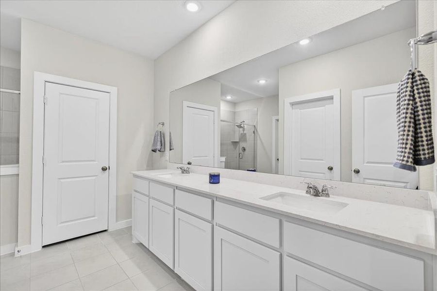 Primary bathroom featuring a shower stall, double vanity, light tile patterned floors, and recessed lighting