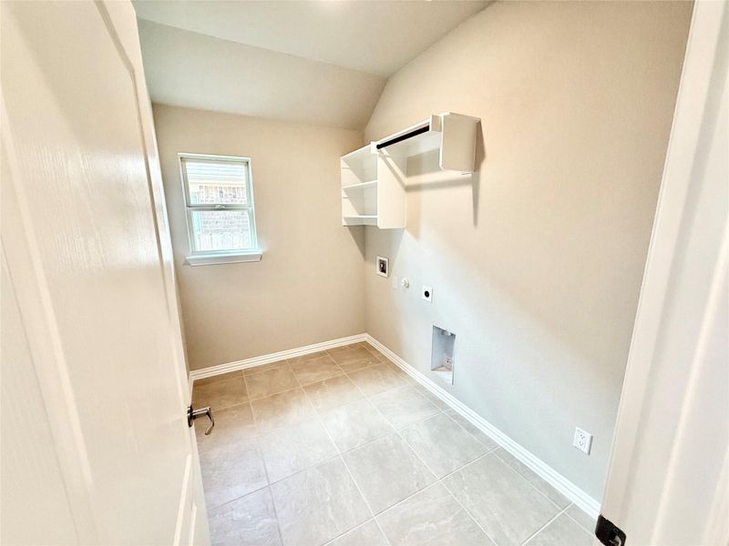 Washroom with electric dryer hookup, light tile patterned flooring, vaulted ceiling, and hookup for a washing machine Washroom with electric dryer hookup, light tile patterned flooring, vaulted ceiling, and hookup for a washing machine