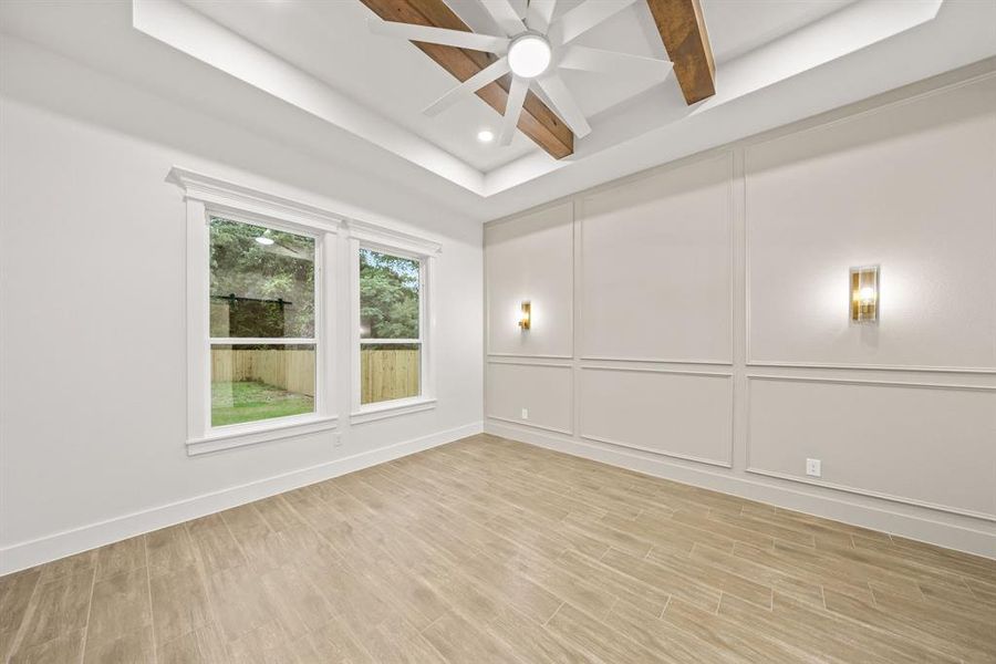 Tray ceiling with exposed wood beams, ceiling fan, and recessed lighting
