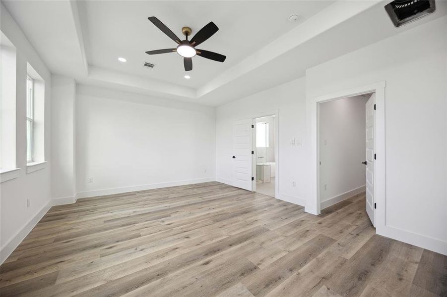 An additional view of the primary bedroom on third floor offering upgraded flooring, modern ceiling fan for added comfort, and convenient access to the primary bathroom.