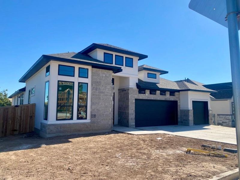 Prairie-style home featuring stone siding, a garage, and driveway