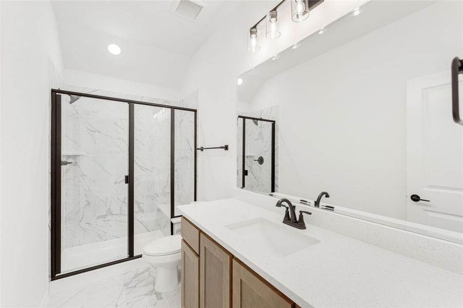 Bathroom with double sink vanity, glass-enclosed marble shower, and black hardware accents