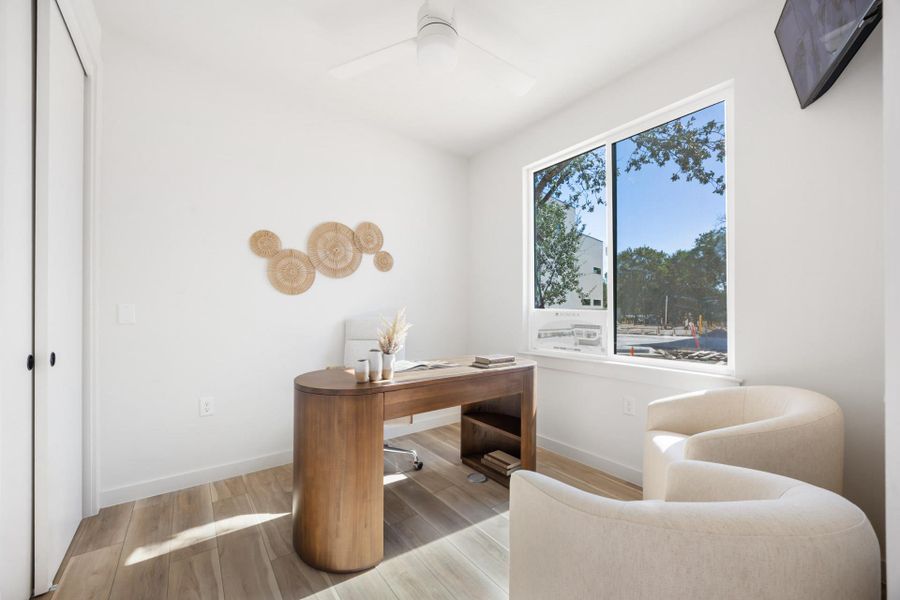 Bright interior space featuring wood-finish flooring, a contemporary ceiling fan, and a large window offering exterior views