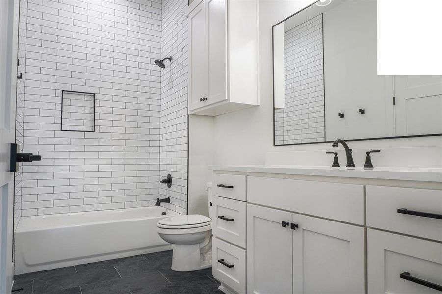 Full bathroom featuring toilet, vanity, and tiled shower / bath