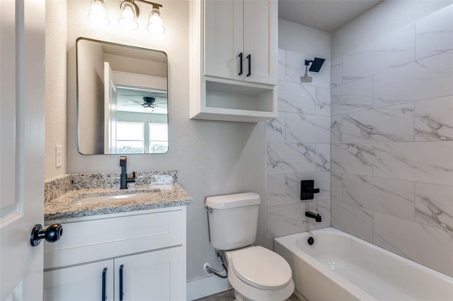 Full bathroom featuring vanity, toilet, ceiling fan, and tiled shower / bath