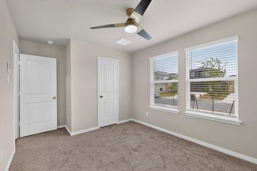 Plentiful natural light streams through double windows onto soft carpeting.