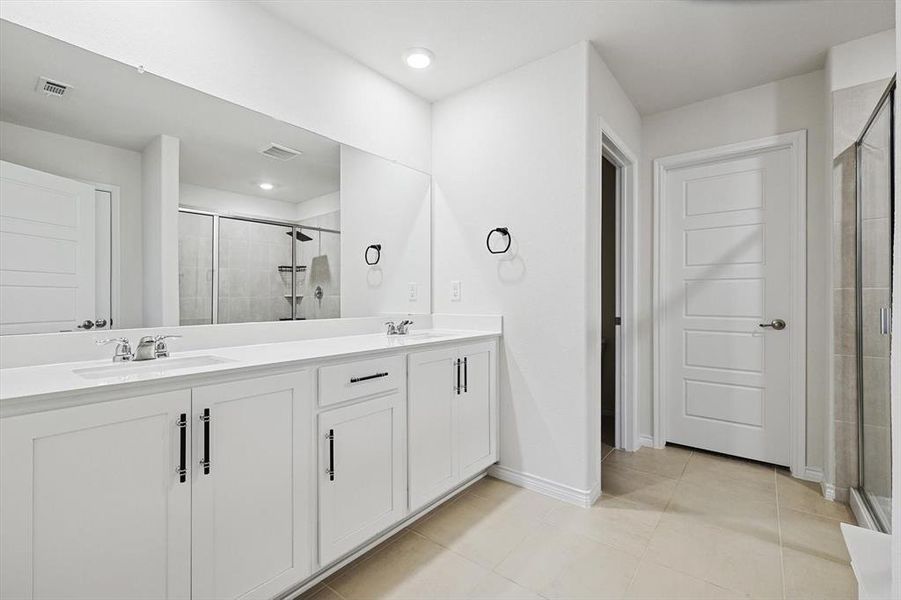 Bathroom featuring tile patterned flooring, vanity, and an enclosed shower