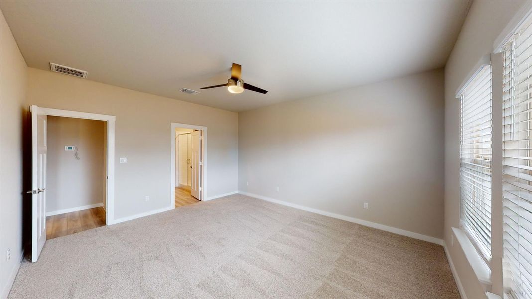 Unfurnished bedroom with light carpet and a ceiling fan