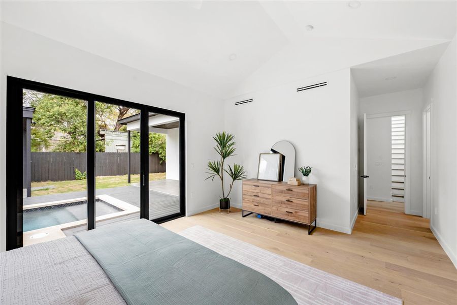 Bedroom with lofted ceiling, light wood-style floors, and access to outside