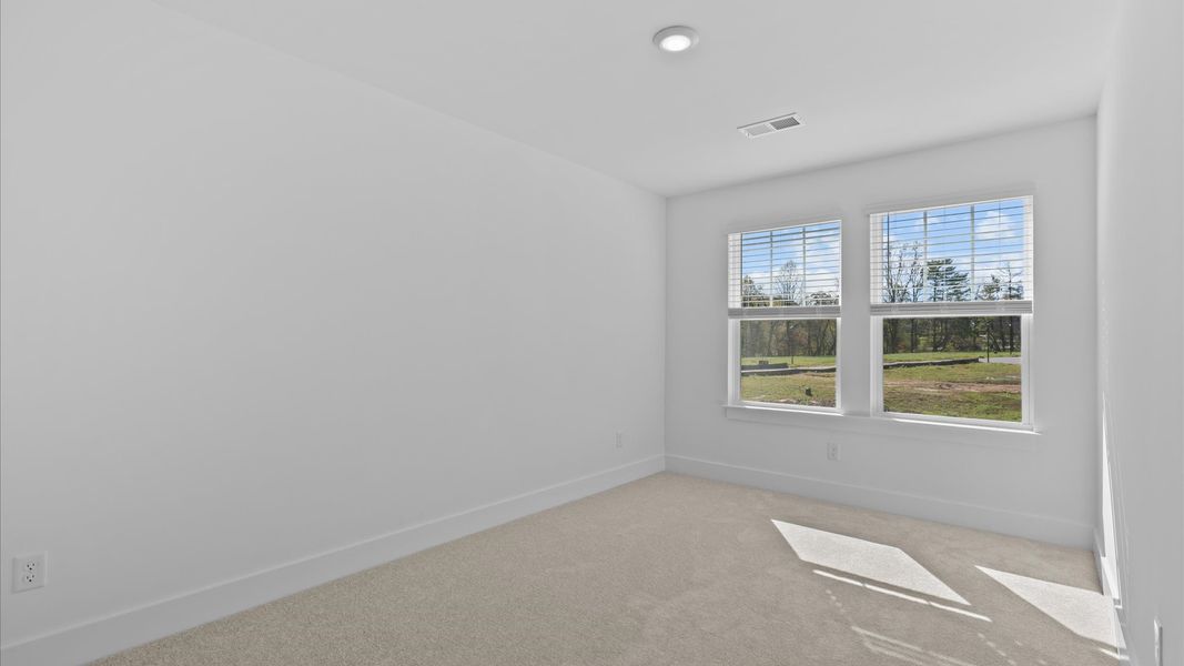Elegant bedroom retreat featuring soft carpet and oversized windows that create a bright, welcoming space
