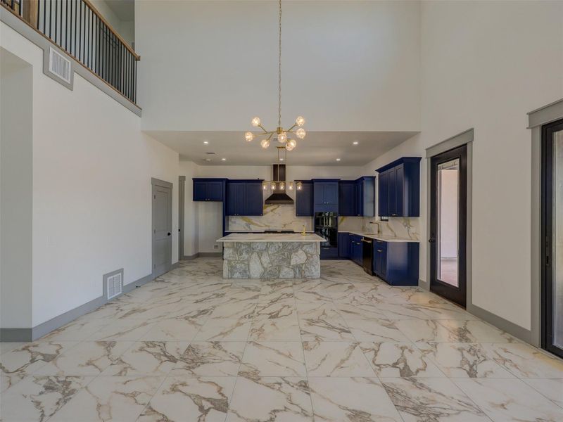 Polished tile flooring and double-height ceilings frame this culinary space centered on a stone island.