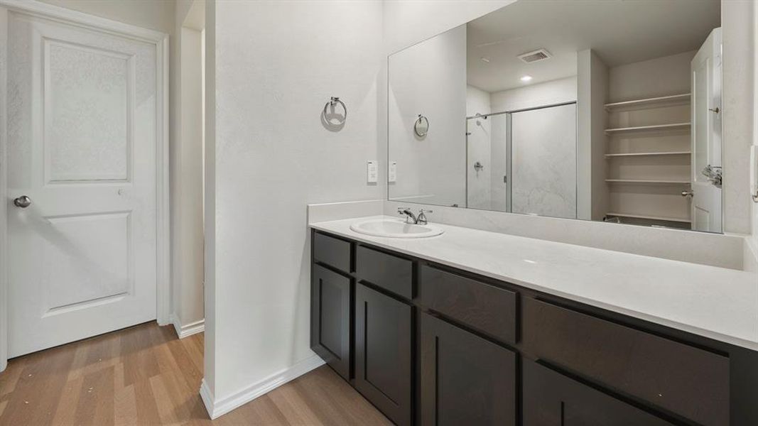 Bathroom featuring a shower stall, vanity, and light wood-style floors