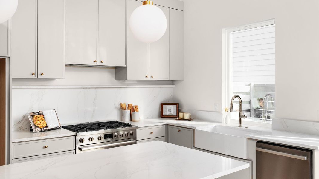 Kitchen with appliances with stainless steel finishes, light stone countertops, and white cabinets