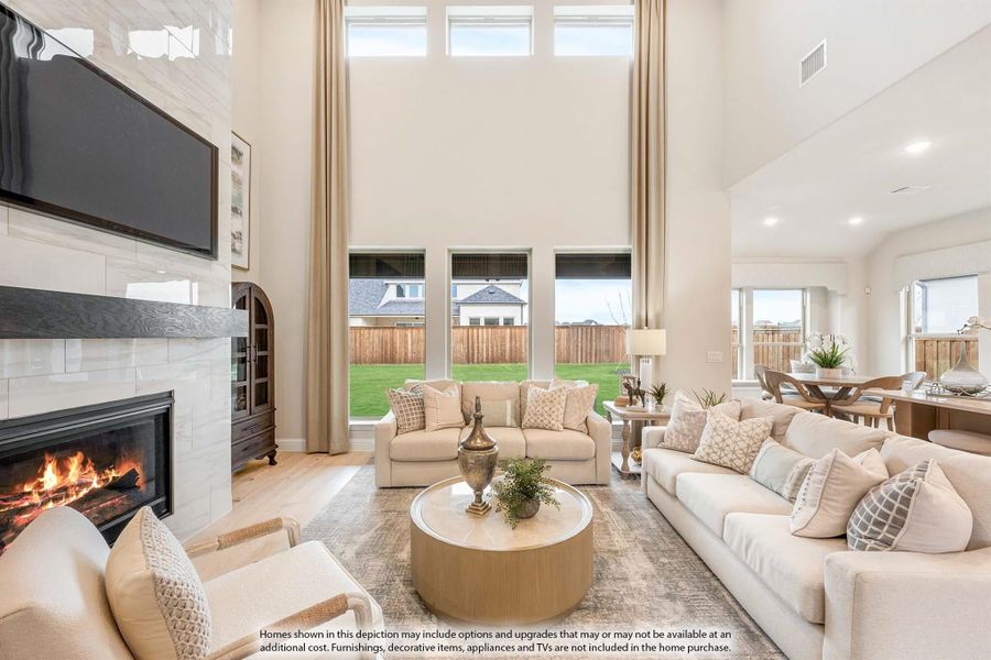 Bright living room with two-story ceiling, tile fireplace, large windows, and neutral furniture