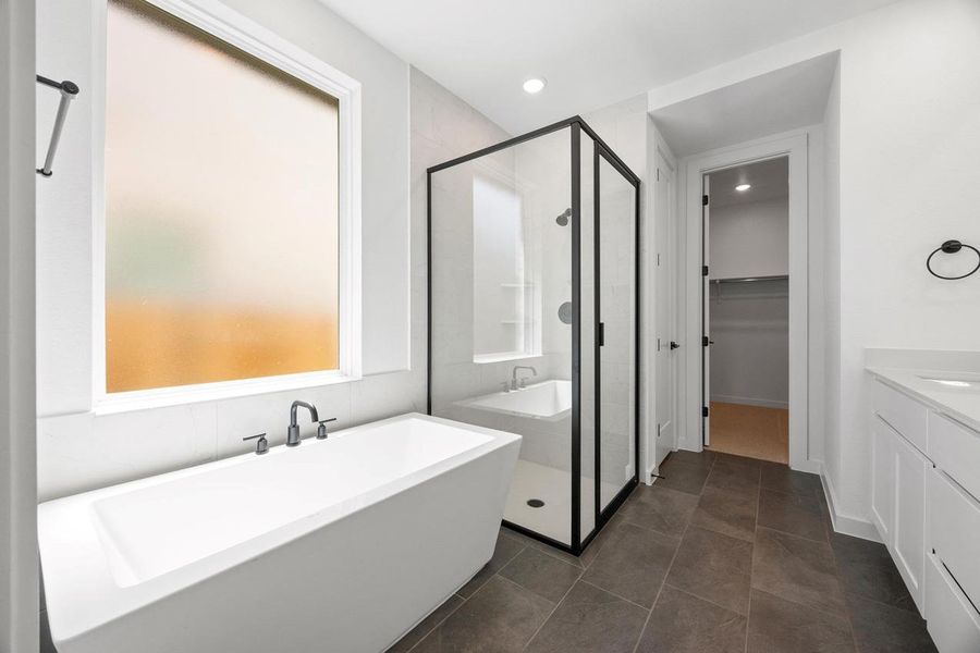 Bathroom with a stall shower, vanity, a freestanding tub, a spacious closet, and dark tile patterned flooring Bathroom with a stall shower, vanity, a freestanding tub, a spacious closet, and dark tile patterned flooring