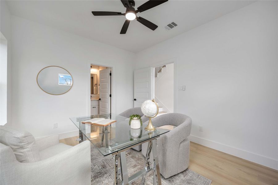 A bright, modern office features a glass desk with cozy textured chairs and white walls that create an open, minimalist feel.