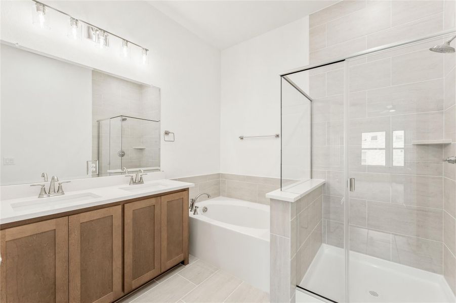 Bathroom with double sink vanity, soaking tub, and glass walk-in shower with gray tile