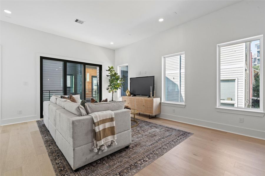 Wrapped in sunlight and anchored by wide-plank flooring, the living area is a serene counterpoint to the home’s bold architectural exterior. Triple-paneled glass sliders frame a covered balcony, blurring the line between indoors and out, while clean walls and natural tones invite personal expression. It's a space designed for slow mornings, lively evenings, and everything in between. Wrapped in sunlight and anchored by wide-plank flooring, the living area is a serene counterpoint to the home’s bold architectural exterior. Triple-paneled glass sliders frame a covered balcony, blurring the line between indoors and out, while clean walls and natural tones invite personal expression. It's a space designed for slow mornings, lively evenings, and everything in between.