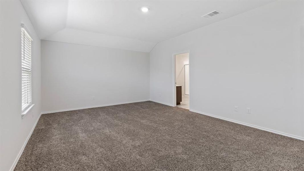 Carpeted spare room featuring vaulted ceiling and baseboards