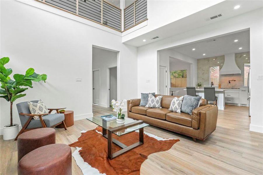 Living room with a towering ceiling, light wood finished floors, and recessed lighting