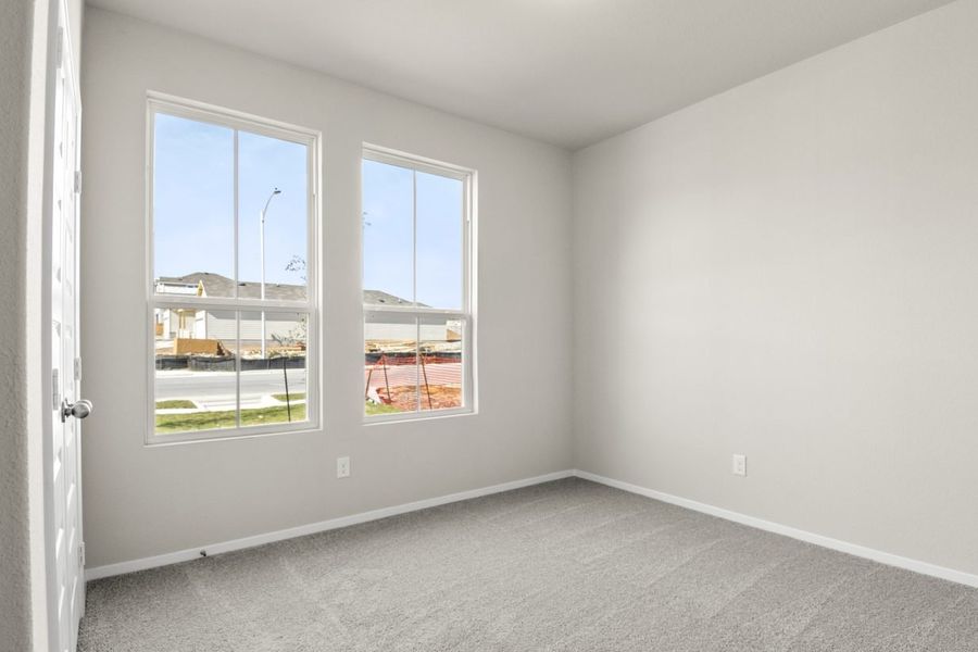 Image of a bedroom with light grey walls, two windows, and tan carpeting