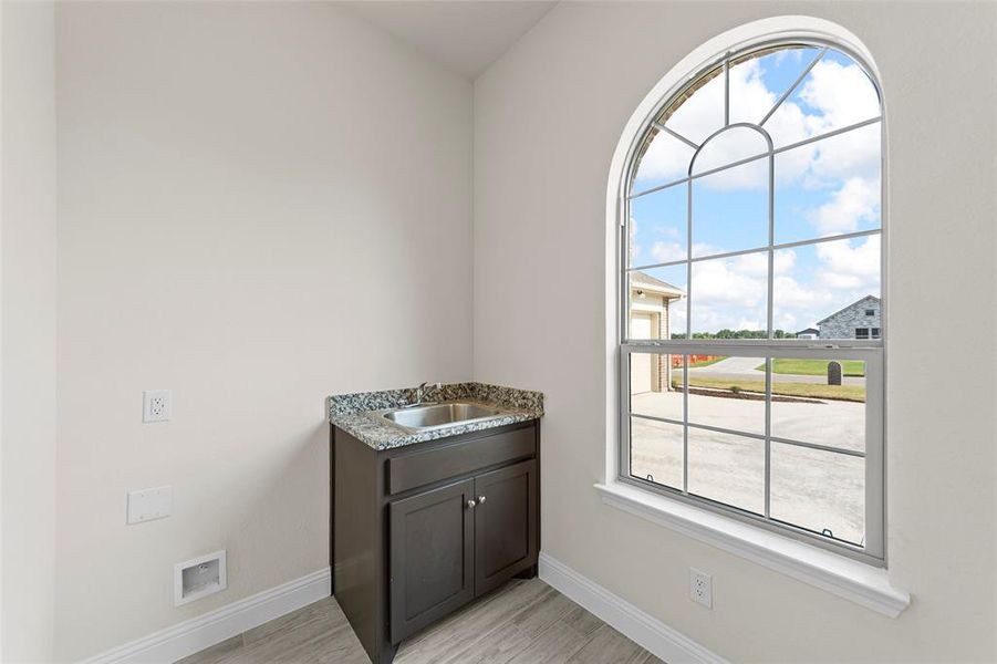 Laundry area featuring sink and light hardwood / wood-style flooring