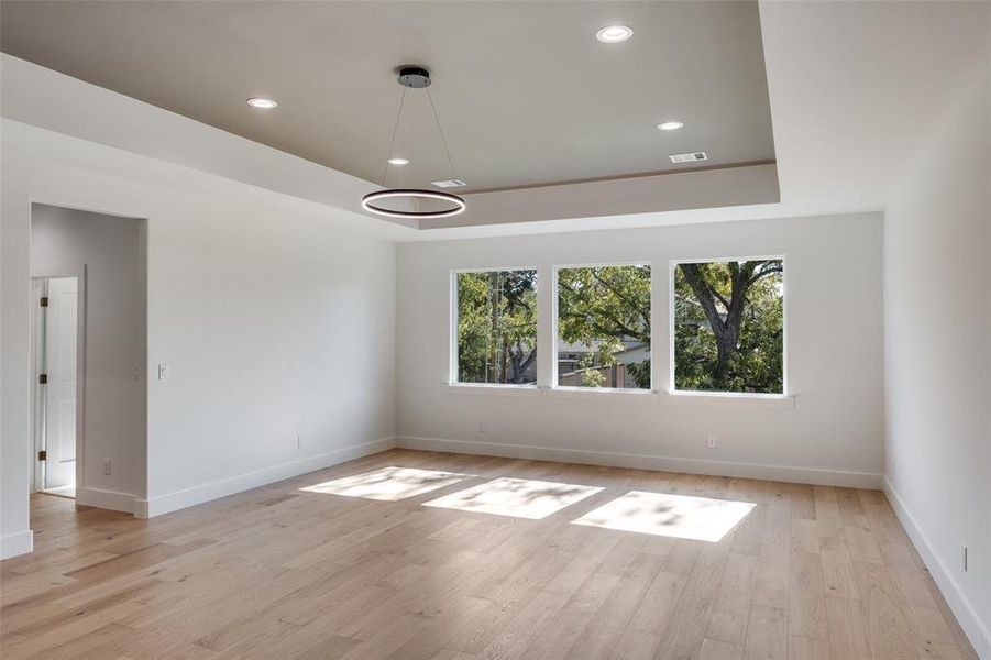 Unfurnished room featuring a tray ceiling, recessed lighting, and light wood finished floors Unfurnished room featuring a tray ceiling, recessed lighting, and light wood finished floors