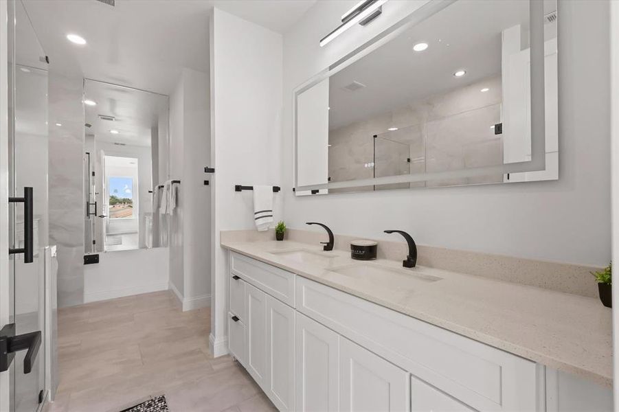 Bathroom with double vanity, a shower with door, and recessed lighting Bathroom with double vanity, a shower with door, and recessed lighting