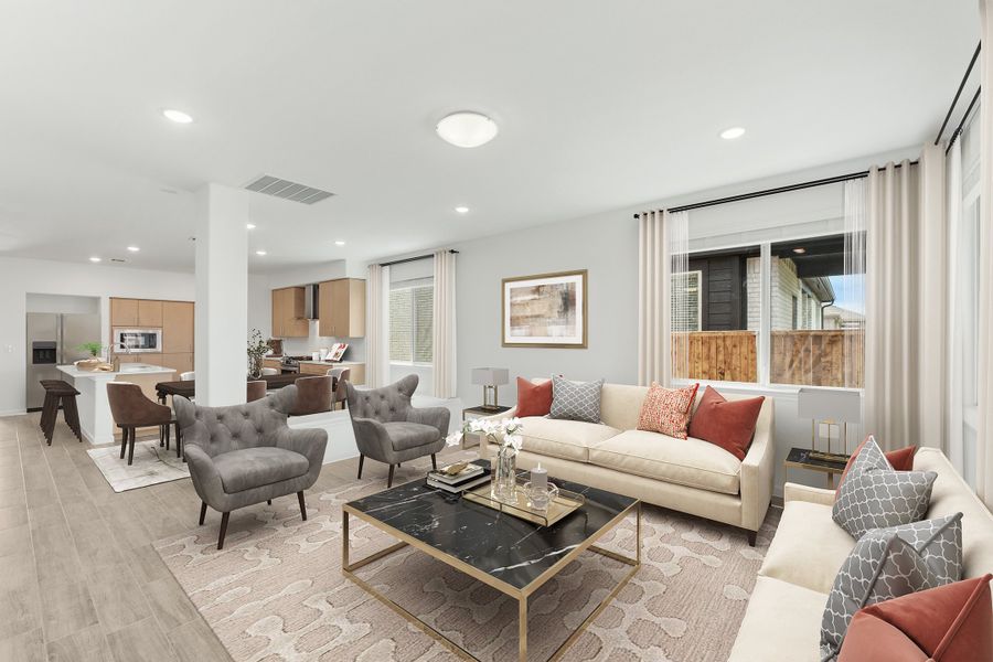 Open-concept living room with cream sofa, gray chairs, marble coffee table, and kitchen visible in background