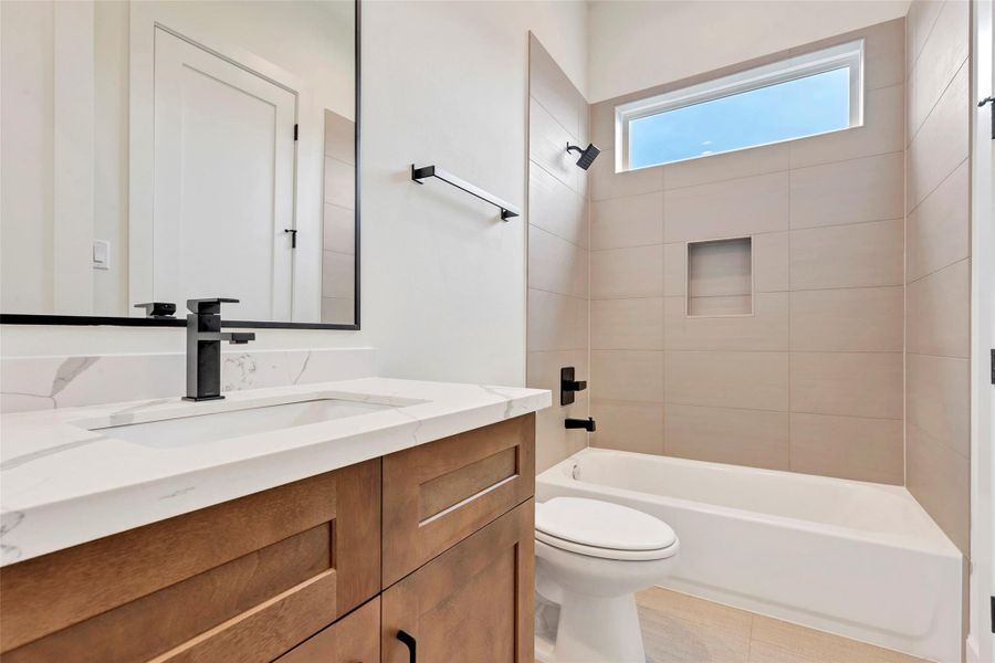 En-suite bathroom featuring a convenient tub and shower combo, along with a sleek single sink and vanity for added comfort and functionality. En-suite bathroom featuring a convenient tub and shower combo, along with a sleek single sink and vanity for added comfort and functionality.