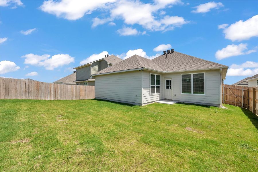 Back of house featuring a shingled roof, a fenced backyard, and a patio area