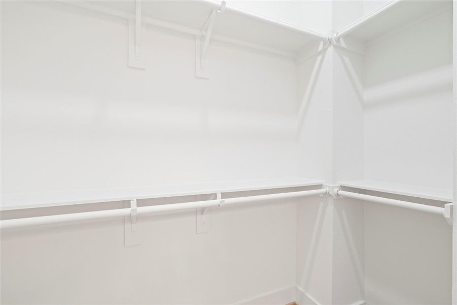 A spacious walk-in closet with double-tier hanging rods and built-in shelving offers functional storage and clean, minimalist design.