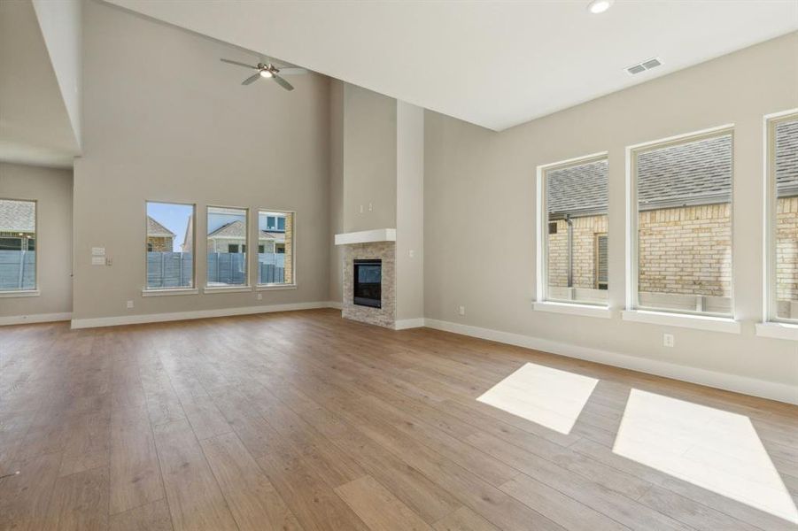 Unfurnished living room with a towering ceiling, light hardwood / wood-style flooring, and ceiling fan