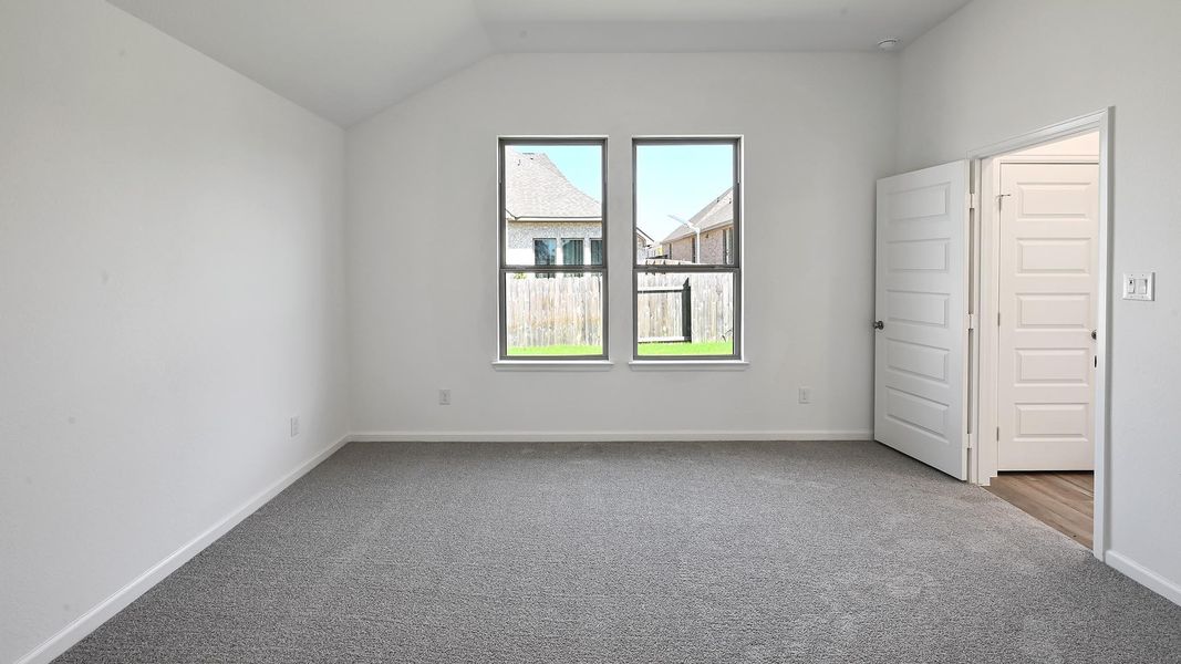 Carpeted empty room with baseboards and vaulted ceiling Carpeted empty room with baseboards and vaulted ceiling