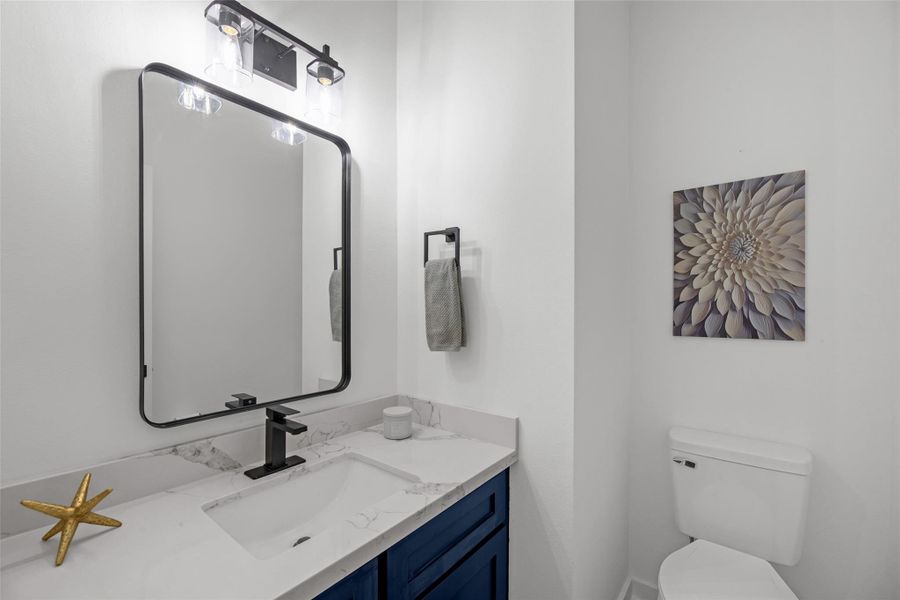 Fashionable bathroom features a sleek white countertop with a black faucet, and large mirror with stylish lighting Fashionable bathroom features a sleek white countertop with a black faucet, and large mirror with stylish lighting